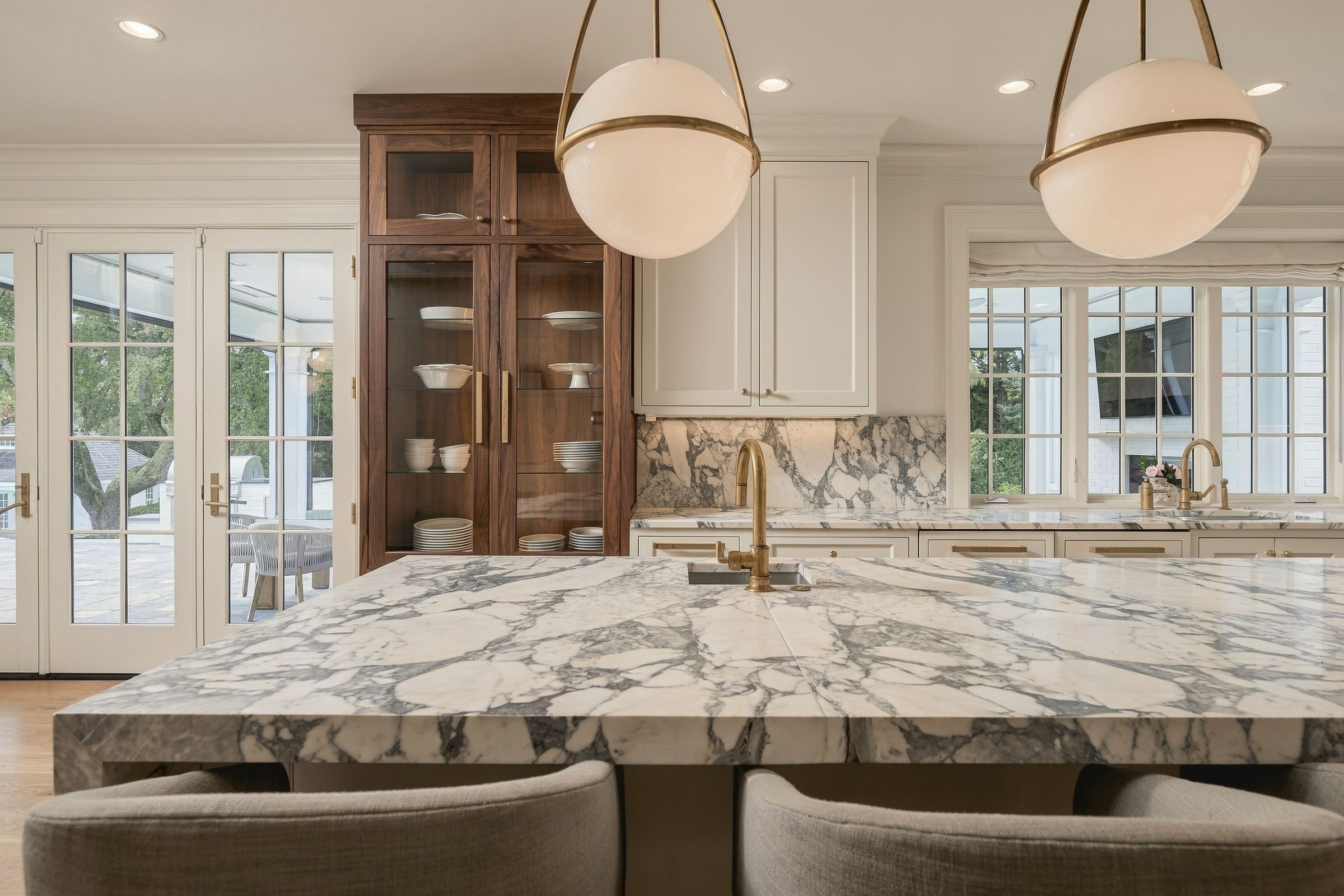 Waterfall marble island and walnut glass-front cabinetry